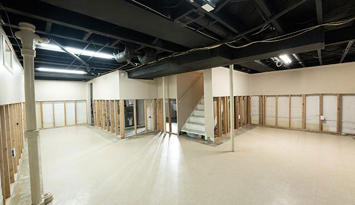 Basement remodeling construction with exposed wall studs and black ceiling